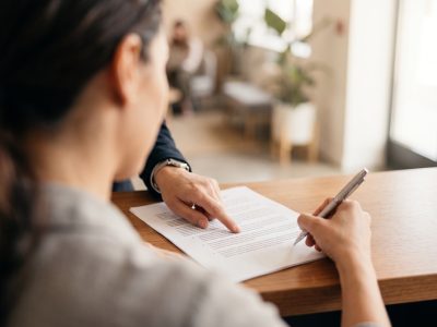 Persona firmando un contrato de matrícula con garantía de aprendizaje en una academia de idiomas