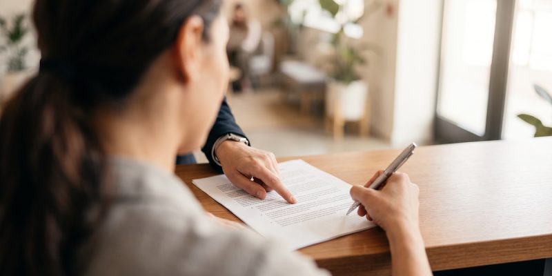 Persona firmando un contrato de matrícula con garantía de aprendizaje en una academia de idiomas