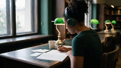 Estudiante latinoamericana preparando el examen JLPT con hojas de práctica de hiragana y kanji