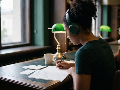 Estudiante latinoamericana preparando el examen JLPT con hojas de práctica de hiragana y kanji
