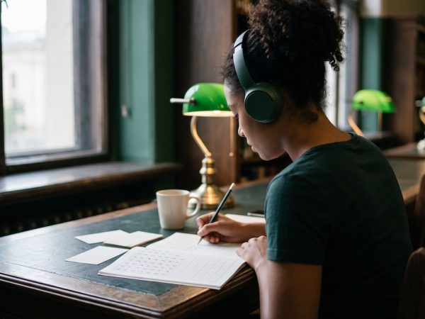 Estudiante latinoamericana preparando el examen JLPT con hojas de práctica de hiragana y kanji
