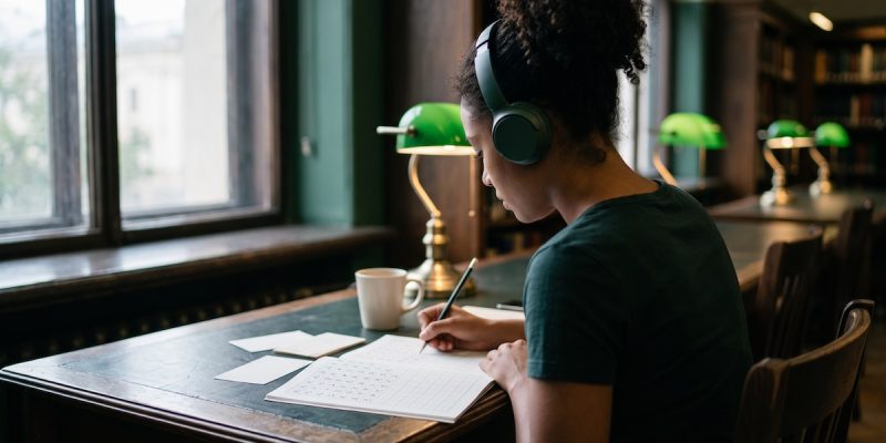 Estudiante latinoamericana preparando el examen JLPT con hojas de práctica de hiragana y kanji