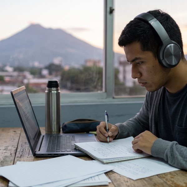 Joven salvadoreño practica con audífonos frente a una laptop para el TOEFL en El Salvador