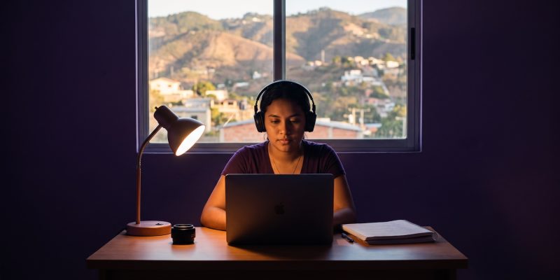 Estudiante hondureña preparando el TOEFL en Honduras con laptop y audífonos