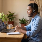 Joven nicaragüense en casa con laptop y audífonos buscando trabajos remotos en inglés